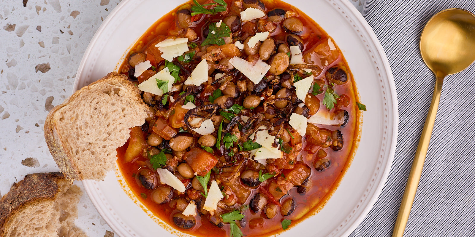 bowl of calypso beans in tomato broth with fried shallots