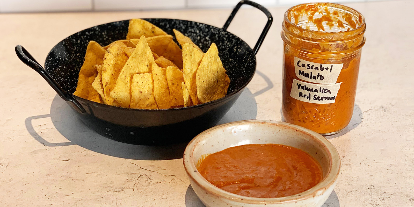 Dried Chili Salsa in a jar next to chips and a bowl of salsa