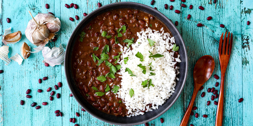 saucy red beans and rice in a bowl on a colorful wood surface.