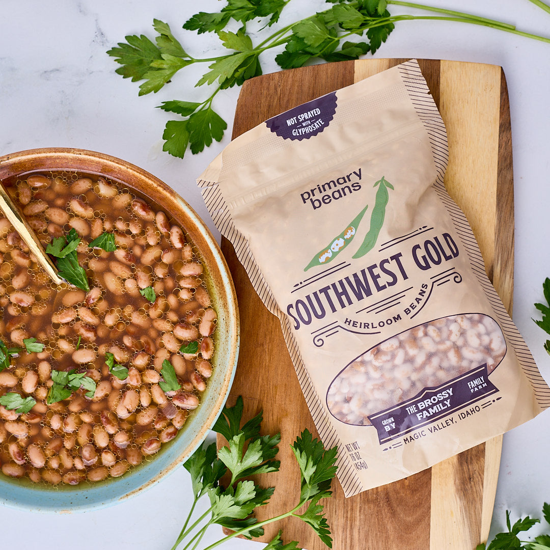 bag of organic heirloom southwest gold beans next to a bowl of cooked heirloom beans