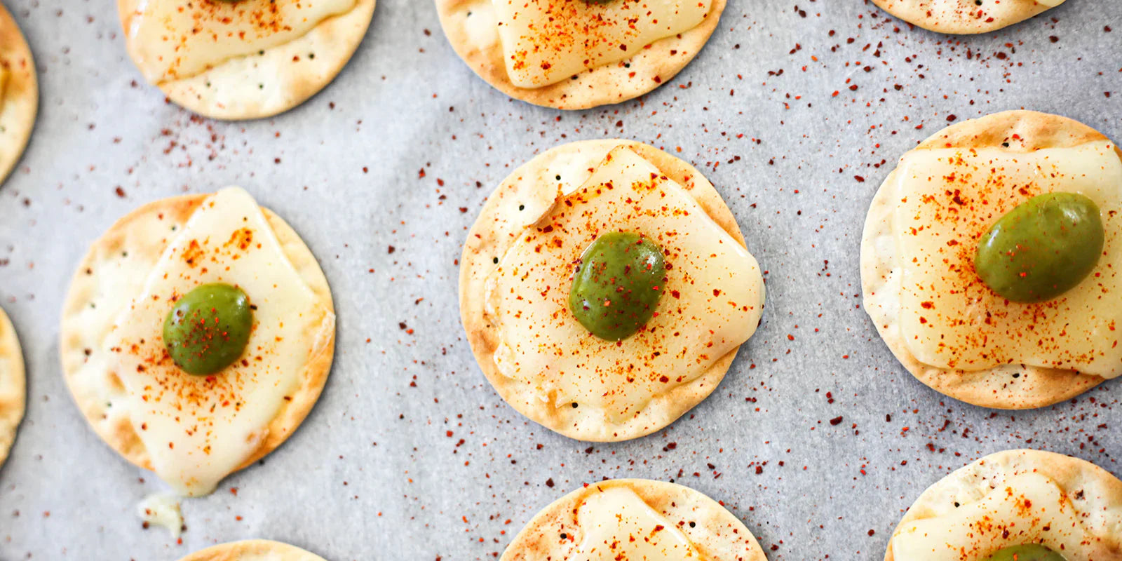 melted cheese on crackers with piment d'espelette and olives