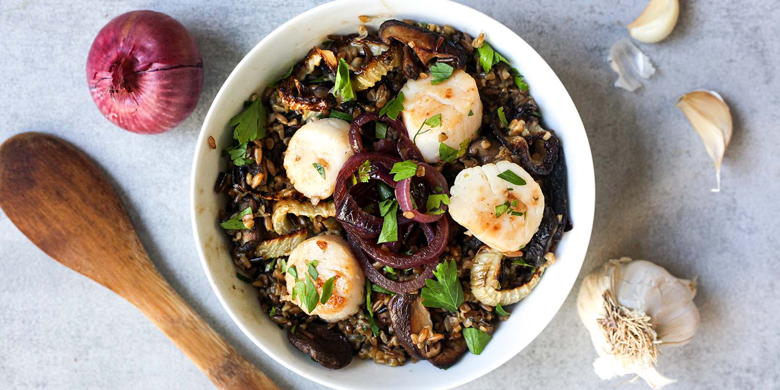 seared scallops served atop potlatch pilaf with balsamic glazed red onions on a ceramic plate