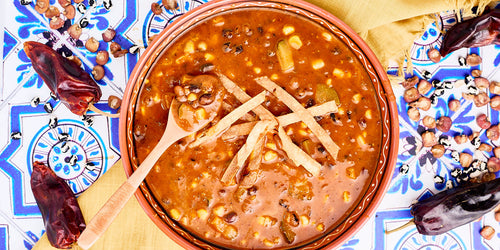 bowl of soup with corn, beans, squash and tortilla strips on top