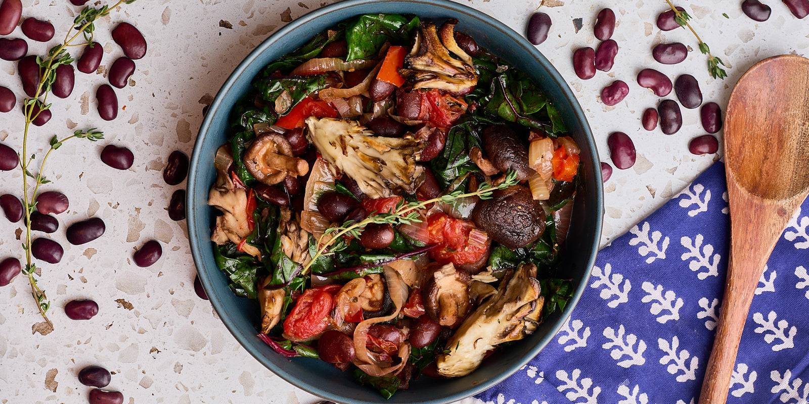 deep purple ayocote beans with mushrooms, chard, thyme and tomatoes in a bowl