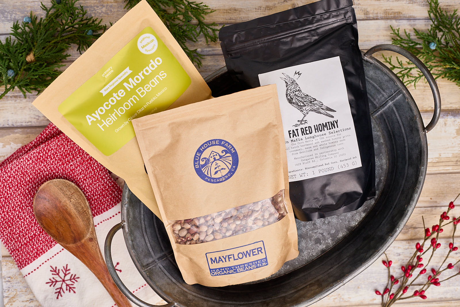 two bags of heirloom beans and one package of hominy in a farm house bucket sitting on a table