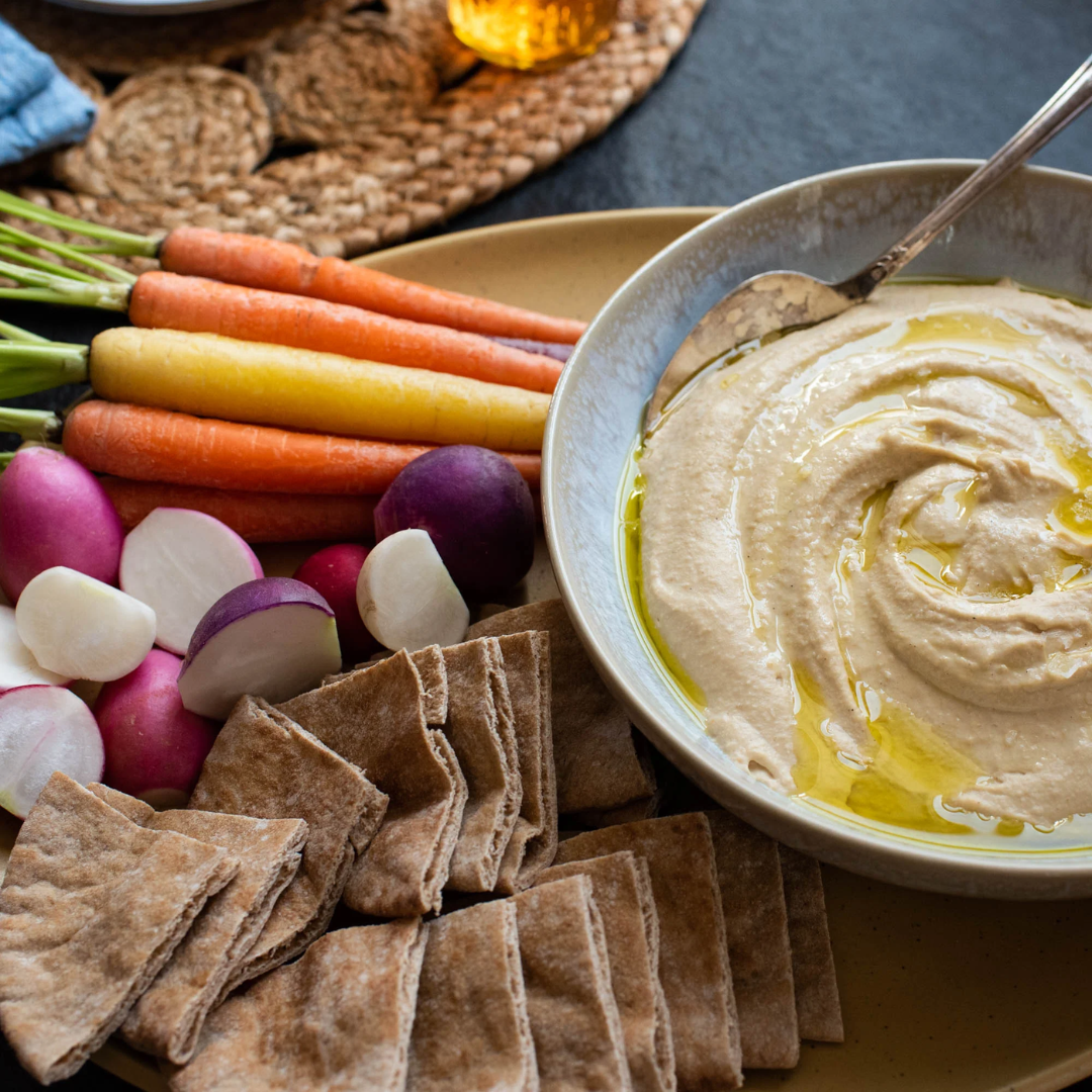Homemade Ultra Creamy Hummus with vegetables and pita on a plate