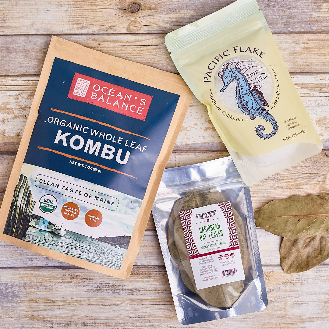 package of kombu, package of caribbean bay leaves and a package of pacific flake sea salt on a wood surface.