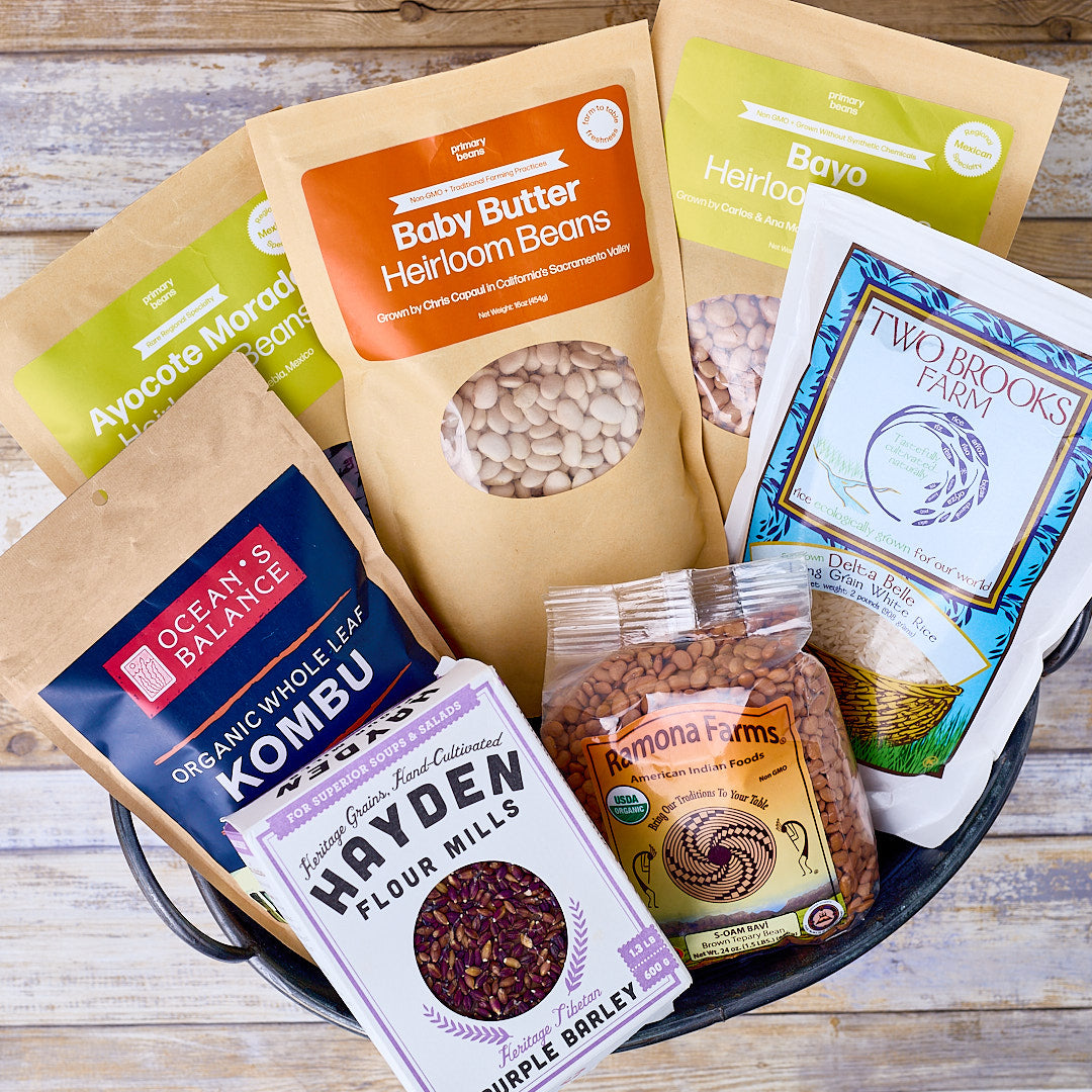 Collection of various packaged heirloom beans and grains on a wooden surface