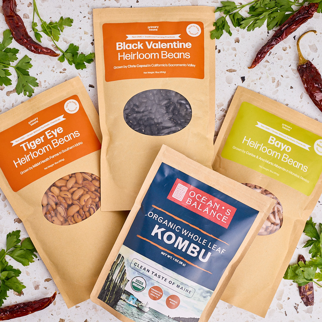 3 packages of heirloom beans and a package of kombu on a counter with seasonings around
