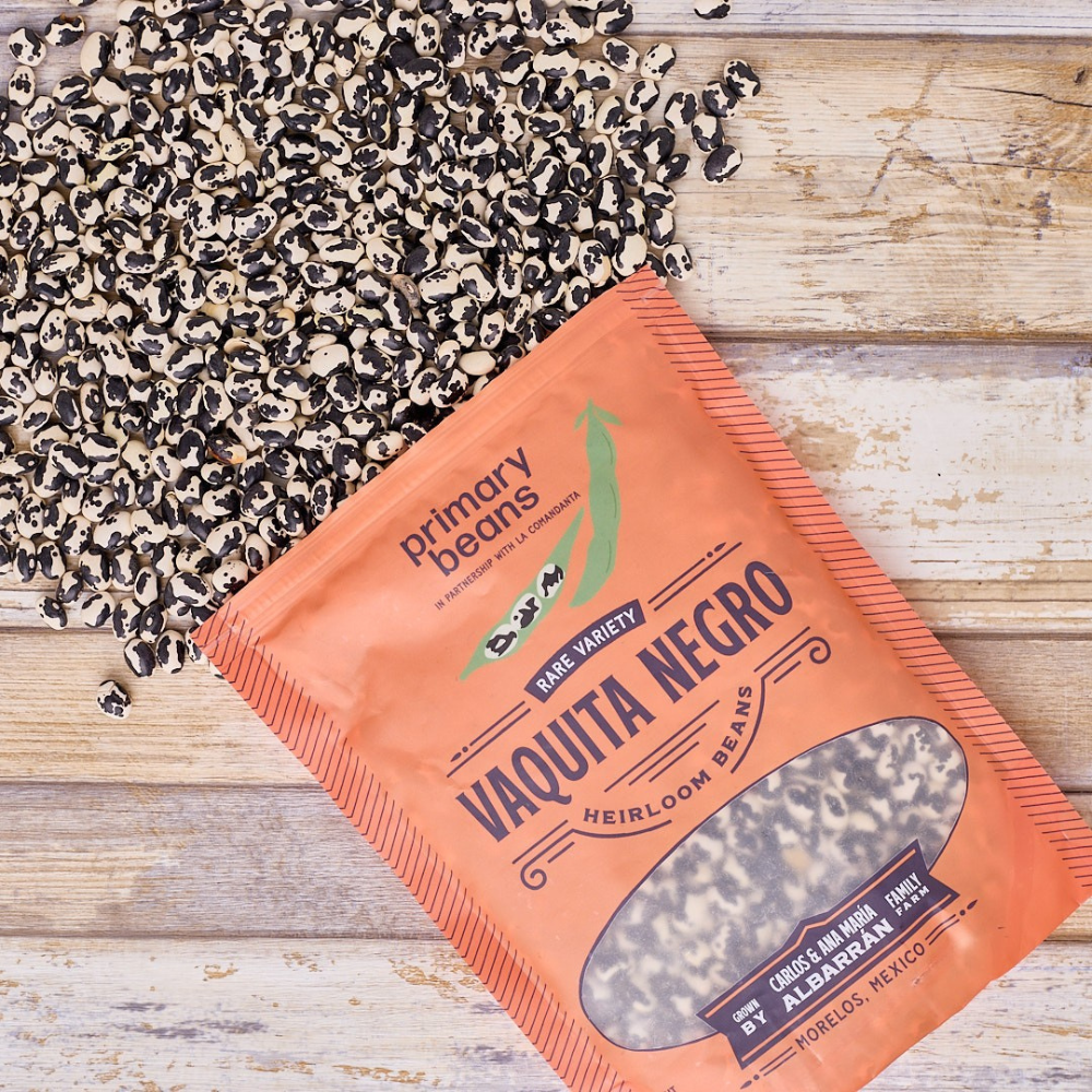 Orange package of 'Vaquita Negro' heirloom beans on a wooden surface