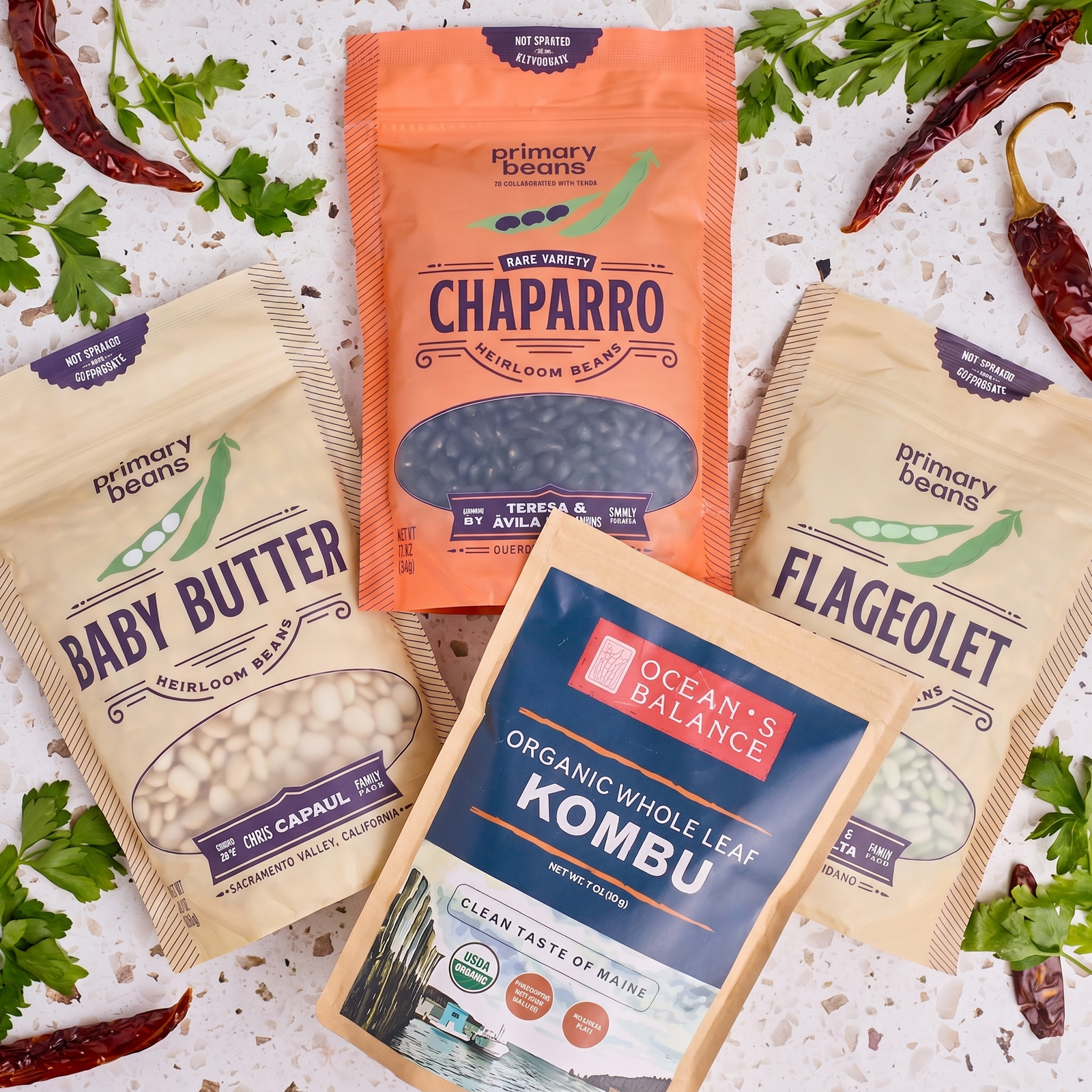 3 packages of beans and a package of kombu on a counter with peppers and parsley around.