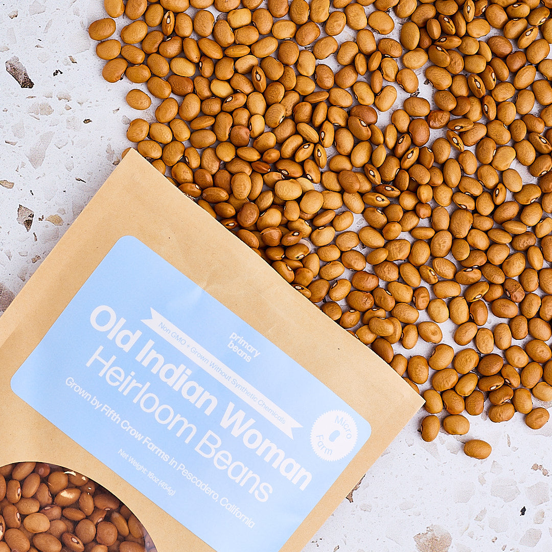 Bag of Old Indian Woman Heirloom Beans with beans spilling out on a light background