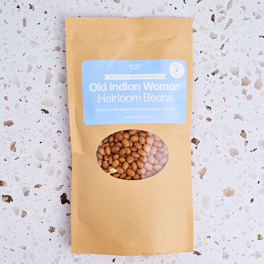 Kraft paper package with window showing beans and blue label on a textured white surface