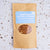 Kraft paper package with window showing beans and blue label on a textured white surface