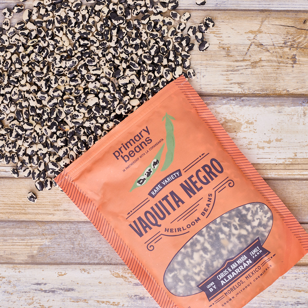 Orange package of 'Vaquita Negro' heirloom beans on a wooden surface