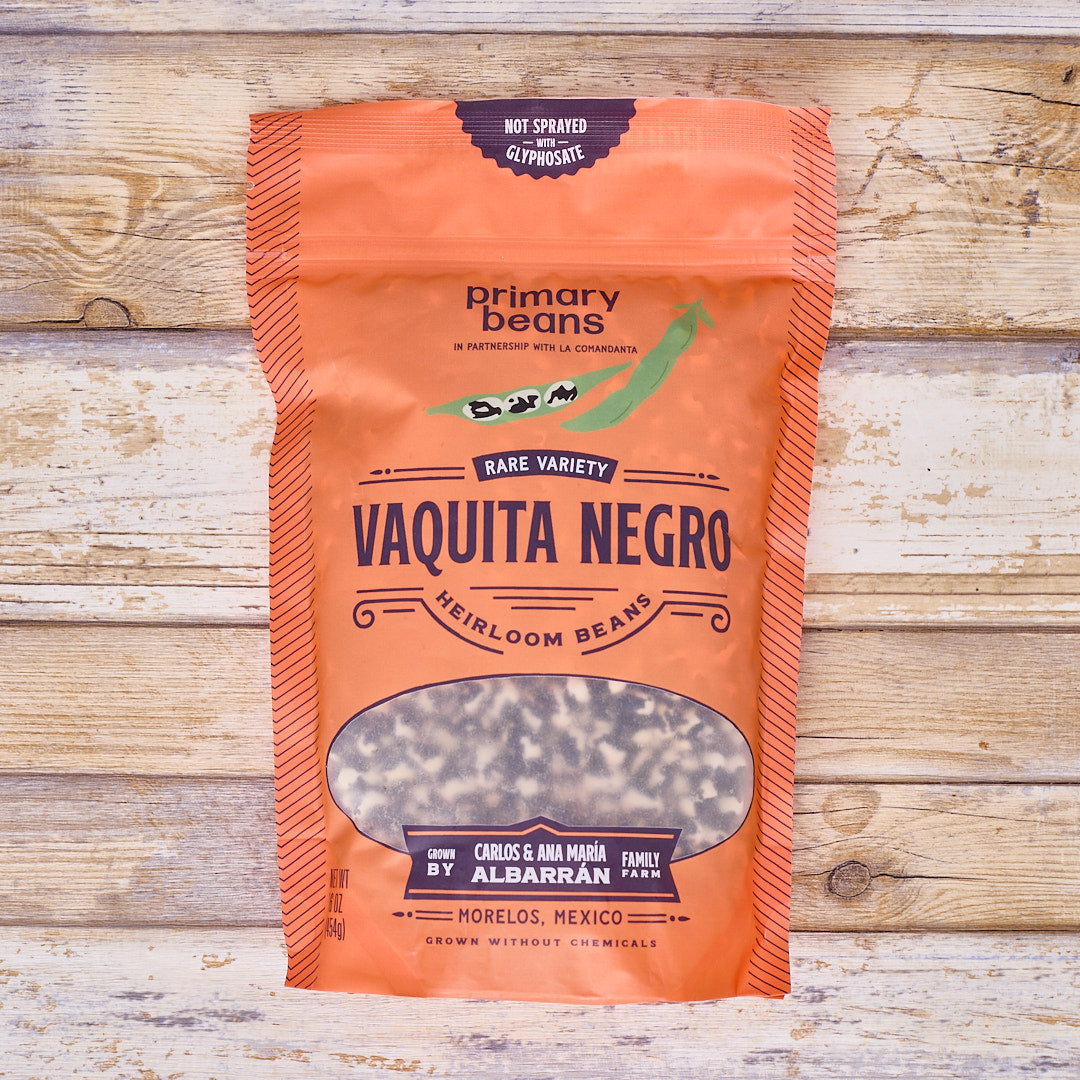 Orange package of 'Vaquita Negro' beans by Primary Beans on a wooden background